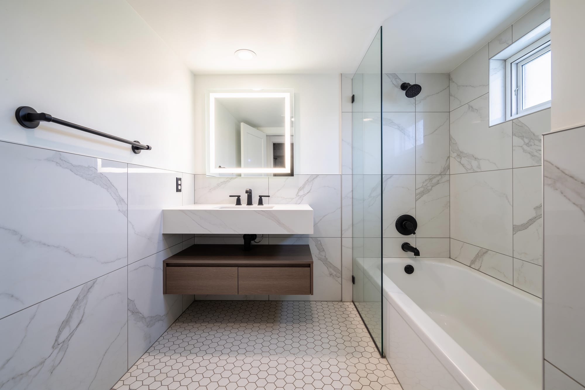 Bathroom after the RANJ remodel — marble-look porcelain walls, floating vanity and hexagon mosaic floor